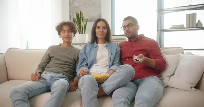 Happy family watches comedy with popcorn sitting on couch