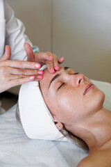 Obraz na płótnie Canvas Pretty yanog woman receiving face massage, closeup photo. Vertical photo. Beautician's office