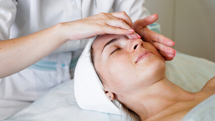 Fototapeta na wymiar Pretty yanog woman receiving face massage, closeup photo. Prevention of skin aging and wrinkles.