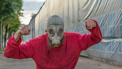 Strange man in a gas mask standing on the street in an empty city. Man wearing anti-pollution,...