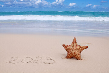 New Year 2023 is coming concept on tropical beach with starfish.