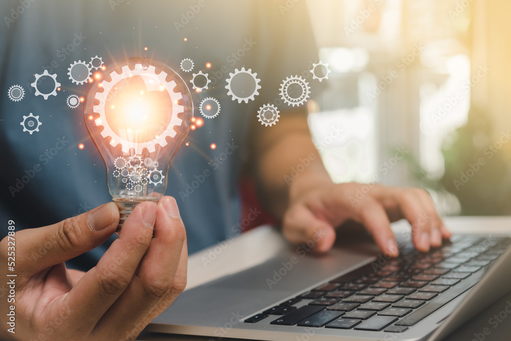 Aufkleber man hand holding lightbulb and a gear icon a notebook computer. using online technology as a source 