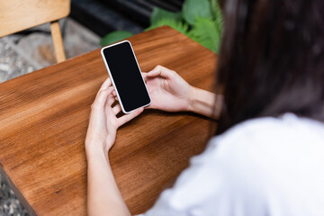 Blurred woman using smartphone in cafe outdoors