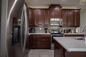  A luxury kitchen with black cabinets, granite counter top, tiled backsplash, stainless steel...