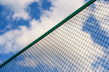 Chain-link fence against the background of the summer sky. Fencing, border, prohibition, protection, territory concept.