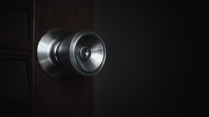 Close up of the keyhole of round door knob background. Slowly open the wooden door into a dark room in the house.