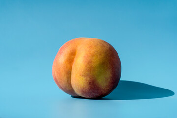 Peach on a blue background as a female body shape like buttocks, thighs, pelvis, pubis. Metaphor of...