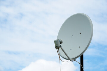 TV satellite dish antenna on a cloudy sky background