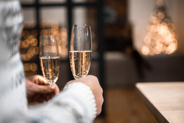 People clinking glasses of champagne against blurred background, closeup. Bokeh effect