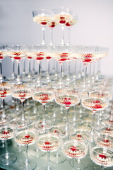 many glasses of champagne with cherries stand on top of each other
