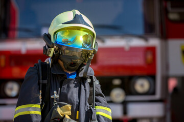 Child, cute boy, dressed in fire fighers cloths in a fire station with fire truck