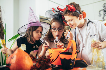 Happy family of mother and children prepare for Halloween pumpkins decorate the home