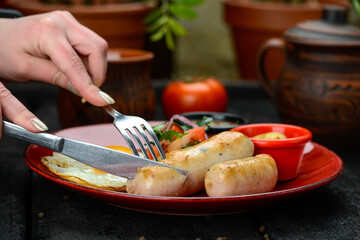 breakfast fried egg with sausage and vegetables in a red plate macro photo
