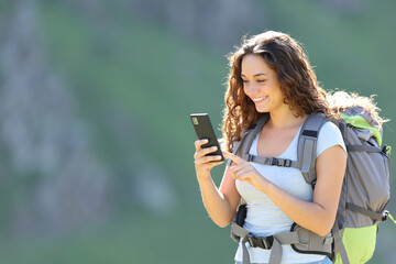 Fototapeta na wymiar Happy hiker consulting smartphone while trekking
