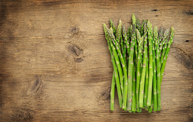 Green asparagus heap on wooden background. Copy space