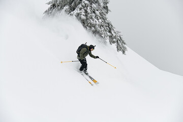 freeride male skier with go-pro camera on his helmet sliding down snow covered slope.