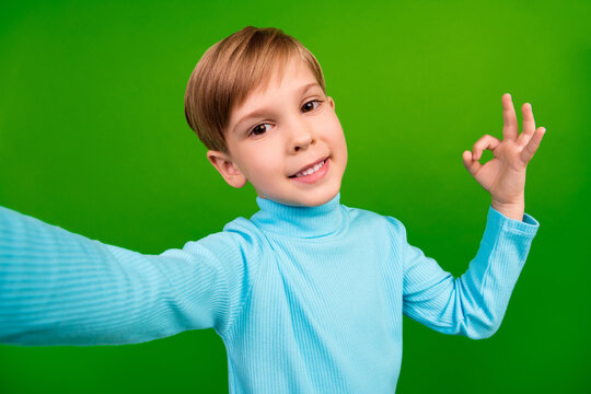 Photo of cheerful sweet little grandson dressed teal turtleneck recoding self video showing okey isolated green color background