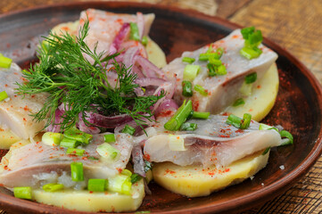 herring fillet on potatoes with onions in a plate macro
