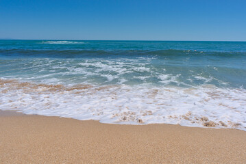 Fototapeta na wymiar Clear emerald green sea with white foam and clean sandy beach