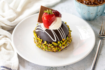 Pistachio and strawberry cake on gray background. Fruit and cream cake covered with chocolate on the outside. close up