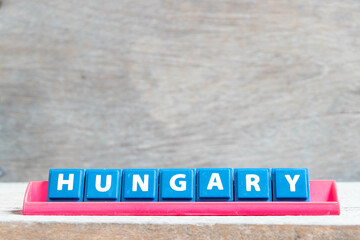 Tile alphabet letter with word hungary in red color rack on wood background