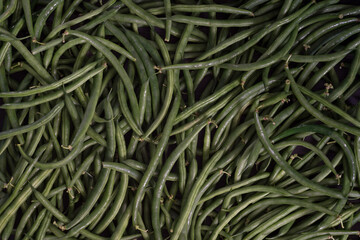 Green string beans close-up on a wooden table. Dark textured background