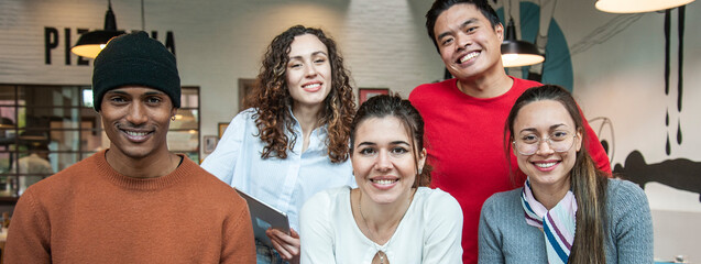 Horizontal banner or header with smiling multiethnic coworkers looking at camera making team picture in multifunctional room of the pizza restaurant for working brunch - Diverse work group - obrazy, fototapety, plakaty