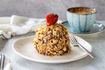 Hazelnut, strawberry and chocolate cake on gray background. Fruit and cream cake covered with chocolate on the outside. close up