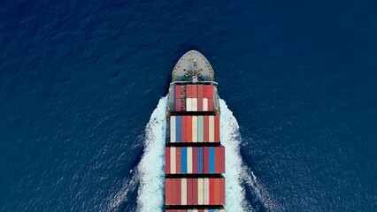 Aerial top down view of a bow from a large container cargo ship traveling with speed over blue ocean - Powered by Adobe