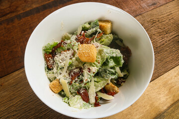 Caesar salad with grilled bacon on white bowl 