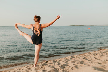 Caucasian woman practicing yoga at seashore sandy beach on sunrise. Womens health and wellness. Sports body positive. Real instructor poses