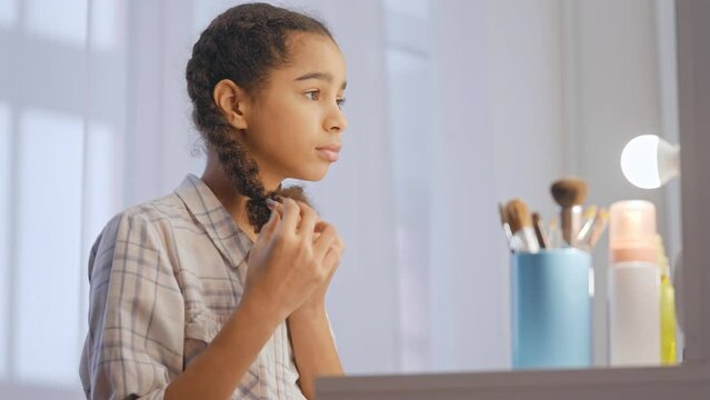 Teenage girl looking in mirror, feeling upset about split ends and dry hair