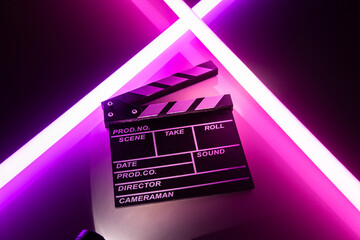 Clapperboard movie slate on Glowing neon lighting background. video director making cinema film....