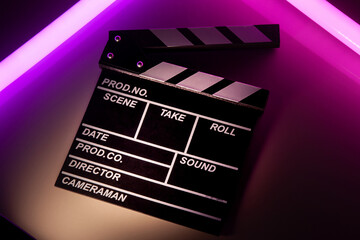 Clapperboard movie slate on Glowing neon lighting background. video director making cinema film....