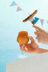 Drinks and snacks. Male hand with glass, mug of cold light beer over light blue sky background....