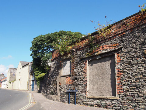 derelict old stone building with blocked up windows, weeds growing from the roof and a street sign in brewery street in ulverston