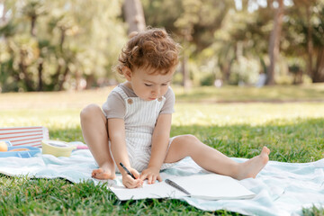 Outdoor portrait of curly baby girl spend time in park with pleasure outdoor. Pretty little lady in summer clothes laughing on blur nature background.