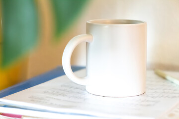 A white mug on a stack of papers - 525352222