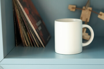 White mug on shelf with vinyls - 525352227