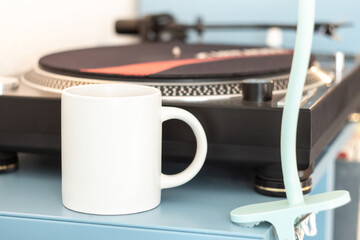 A white mug on a shelf near a vinyl record player