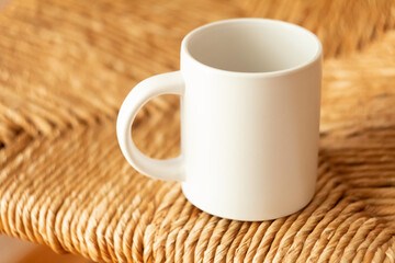 A white mug on a wicker chair - 525352236