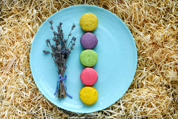  Top view of colorful macaroons on blue plate, decorated with lavender flowers, placed on...