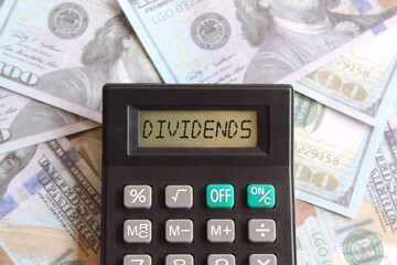 Fototapeta premium Top view image of calculator with text DIVIDENDS and money. Business and finance concept