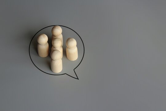 Wooden dolls and speech bubble. Active discussion, cooperation and collaboration, development of joint solution, consensus concept.