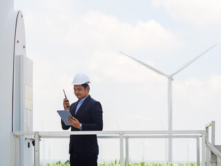 Engineer man manager in a suit is using a tablet to control and monitor the operation of a wind...