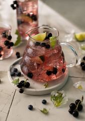 Refreshing ice tea with lime,black currant,carcade,mint leaves and ice cubes in glass tea pot.Close...