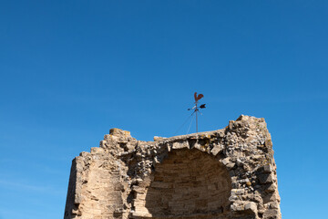 The top of the ruined tower with a weather vane against the sky.