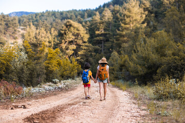 A child with mom walks along a forest path