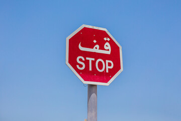 stop sign in arabic. Stop sign with the text in Arabic in the city of Dubai, United Arab Emirates. View from Bajaoj of the Arabic stop sign with blue sky behind