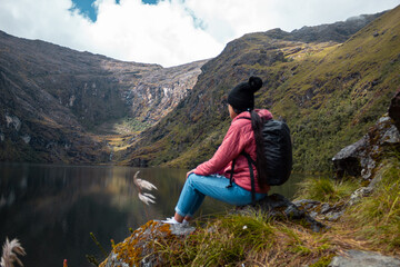 Naklejka premium Mujer reflexionando contra un lago rodeado de montañas